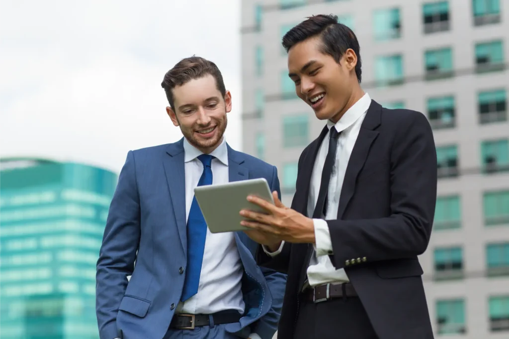 Two guys smiling looking at tablet